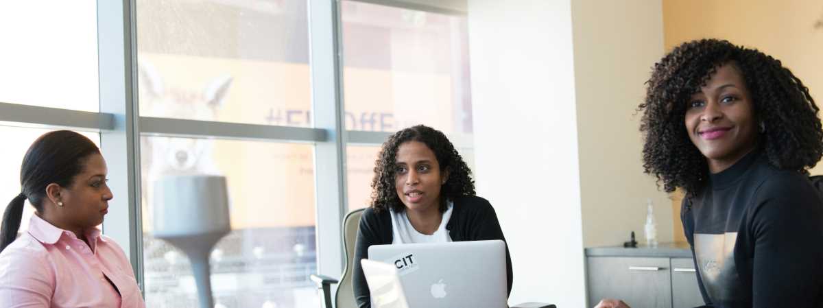 This is an image of three woman working together in a conference room.